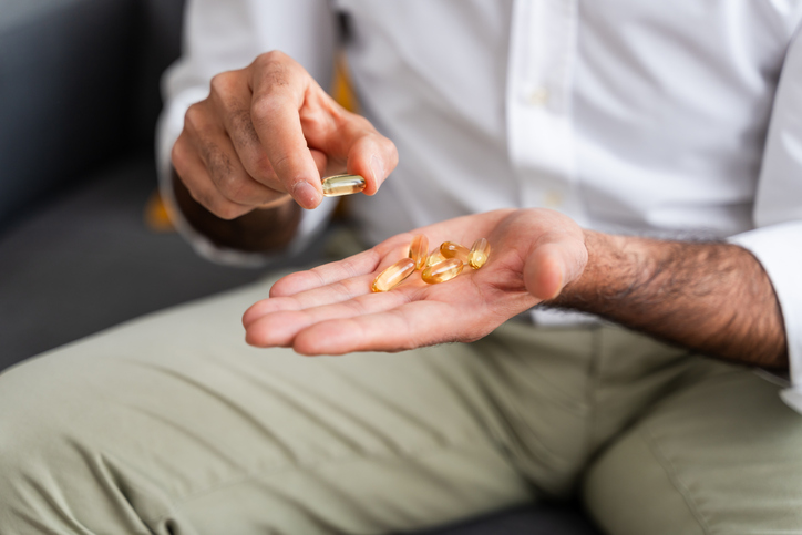 Man met omega 3-capsules in zijn handen.