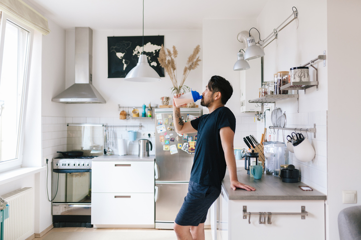 Man drinkt een proteïne shake in zijn keuken.