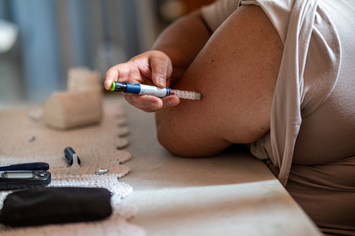 Iemand injecteert insuline in de arm aan tafel.